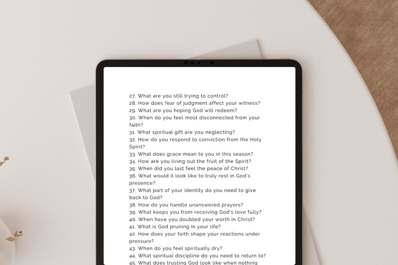 May include: A black tablet displays a list of questions about faith and spirituality. The questions are numbered and written in black text on a white background. The tablet is on a white surface with a neutral background.