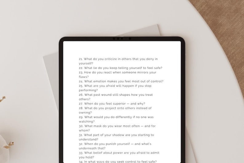 May include: A black tablet shows a list of self-reflection questions in white text. The questions, numbered, focus on personal growth and self-awareness. The tablet is on a white surface.