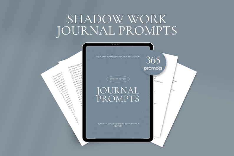 May include: A digital journal with the text "Shadow Work Journal Prompts" and "Journal Prompts" on the screen. The screen displays 365 prompts for self-reflection. Two sheets of paper with prompts are on either side of the tablet.