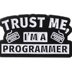 Könnte beinhalten: Schwarz-weißer Patch mit dem Text "Vertrau mir, ich bin ein Programmierer" mit einem Tastatursymbol auf jeder Seite.