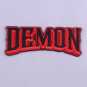 May include: Red embroidered patch with the word "DEMON" in black outlined letters.