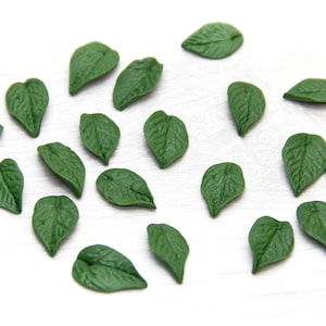 Pode incluir: Uma coleção de 20 enfeites de folhas verdes, perfeitos para artesanato e decoração. Cada folha é feita de um material macio e flexível e tem uma textura realista.
