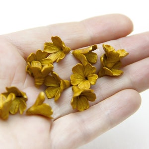 May include: A collection of small, gold-colored flower embellishments, perfect for adding a touch of elegance to crafts and projects.