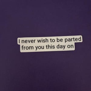 Puede incluir: Una pegatina blanca con el texto "I never wish to be parted from you this day on" en negro. La pegatina es rectangular y está sobre un fondo morado.