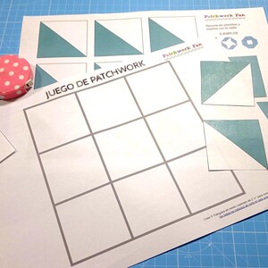 Puede incluir: Un tablero de juego blanco con el título "JUEGO DE PATCHWORK" impreso en negro. El tablero está dividido en nueve cuadrados. Hay varias formas triangulares azules y blancas sobre el fondo blanco.