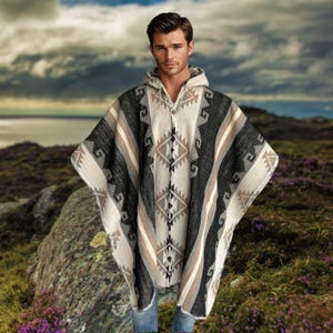 Könnte beinhalten: Ein Kapuzenponcho mit einem geometrischen Muster in Schwarz, Weiß und Beige. Der Poncho hat ein zentrales Rautenmuster und gestreifte Akzente. Das Kleidungsstück besteht aus einem dicken, gewebten Material, das für kühleres Wetter geeignet ist.