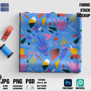Puede incluir: Una pila de maquetas de tela con un patrón abstracto colorido sobre un fondo azul. La tela está doblada y apilada sobre una superficie blanca. La imagen incluye el texto "FABRIC STACK MOCKUP".