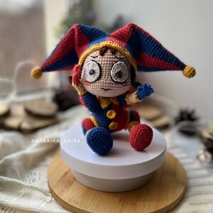 Amigurumi crochet clown Pomni toy, perfect for DIY Halloween decorations or a fun, spooky crochet gift. Detailed close-up showing intricate stitching and bright color palette.