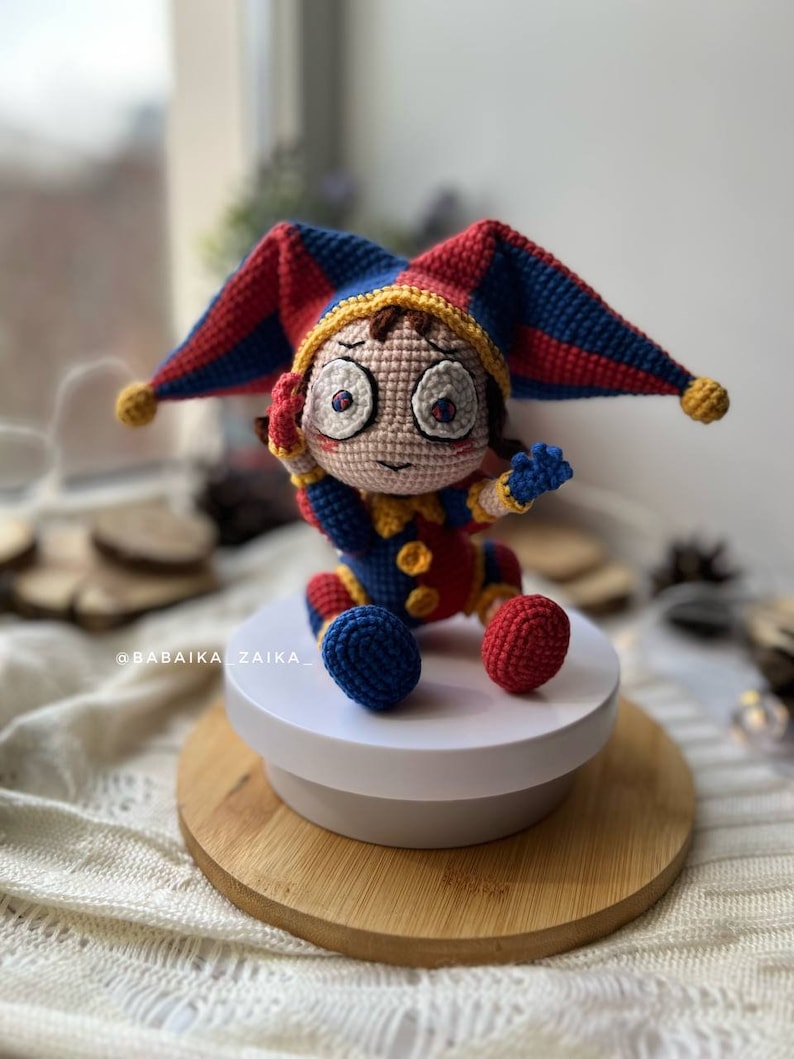 Amigurumi crochet clown Pomni toy, perfect for DIY Halloween decorations or a fun, spooky crochet gift. Detailed close-up showing intricate stitching and bright color palette.