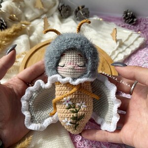 Amigurumi butterfly doll holding a delicate crochet flower, symbolizing care and craftsmanship. This DIY pattern is ideal for those seeking a heartfelt handmade gift that showcases love and eco-conscious creativity.