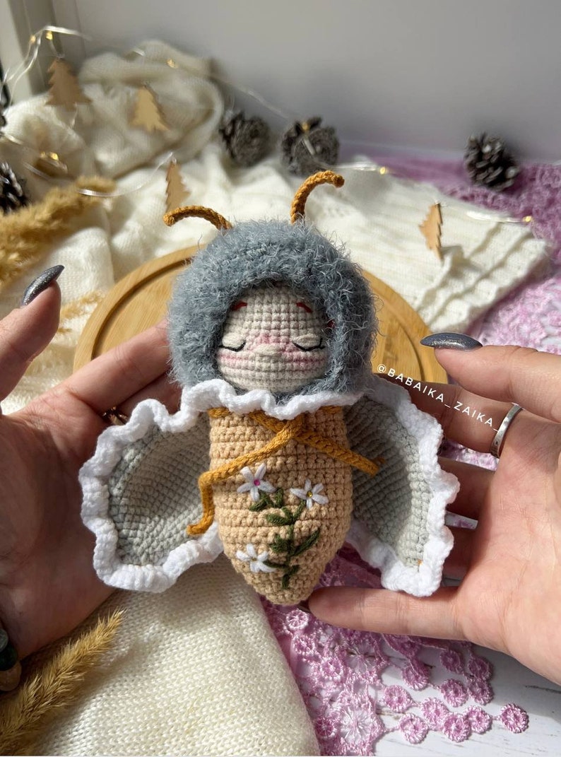 Amigurumi butterfly doll holding a delicate crochet flower, symbolizing care and craftsmanship. This DIY pattern is ideal for those seeking a heartfelt handmade gift that showcases love and eco-conscious creativity.