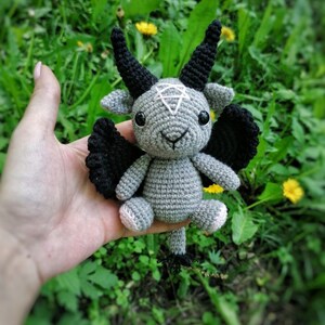 Crochet Baphomet toy held in hand with a green natural background, emphasizing the intricate details and handmade quality.