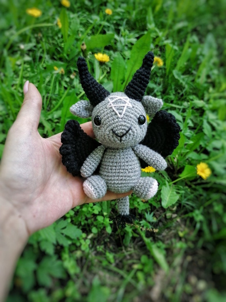 Crochet Baphomet toy held in hand with a green natural background, emphasizing the intricate details and handmade quality.