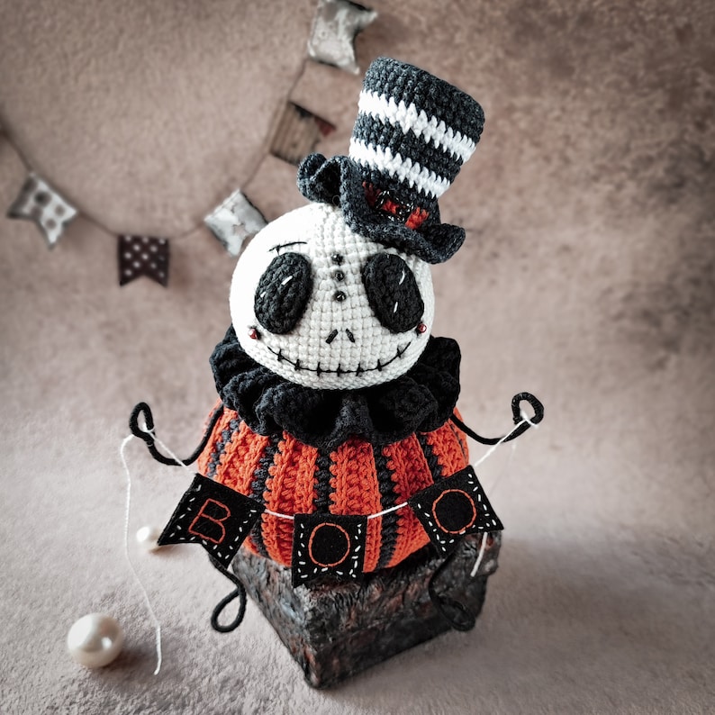 A cozy and eerie Halloween setup with the Jack pumpkin amigurumi figure as the centerpiece. The "BOO" sign, top hat, and spooky details make it a perfect handmade Halloween decoration.