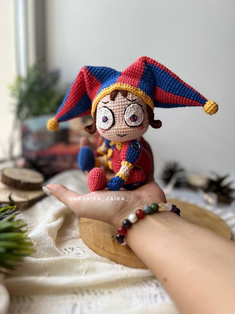 Side angle view of Pomni crochet clown amigurumi, featuring vibrant color tones and a spooky, fun design. Perfect for enhancing Halloween party decor or gifting to handmade toy lovers.