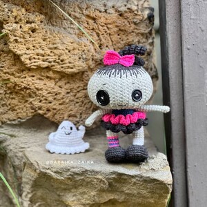 The crochet doll placed on stone stairs, creating a spooky yet charming atmosphere. The ghost companion is attached to its hands, making it a perfect Halloween amigurumi pattern for beginners and advanced crocheters.