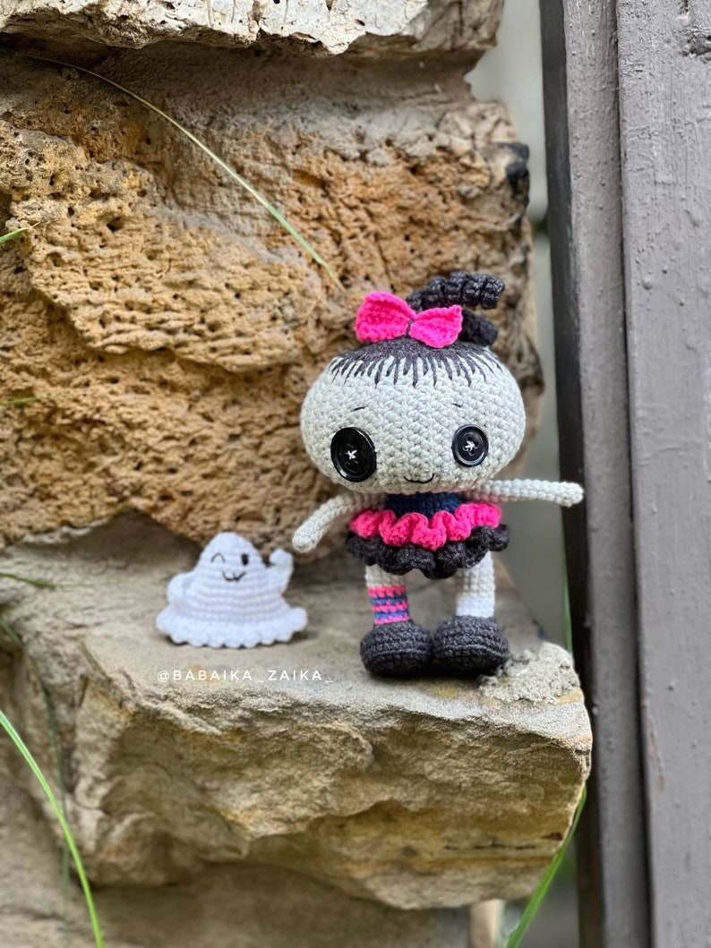 The crochet doll placed on stone stairs, creating a spooky yet charming atmosphere. The ghost companion is attached to its hands, making it a perfect Halloween amigurumi pattern for beginners and advanced crocheters.