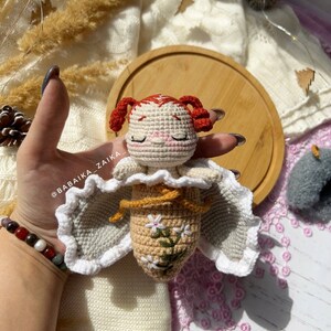 The completed crochet doll sitting upright, radiating handmade charm. This amigurumi butterfly baby is perfect for unique DIY gifts, adding a personal touch and thoughtful creativity to your crafts.