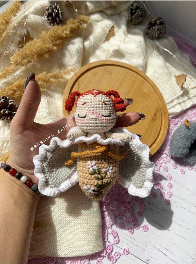The completed crochet doll sitting upright, radiating handmade charm. This amigurumi butterfly baby is perfect for unique DIY gifts, adding a personal touch and thoughtful creativity to your crafts.