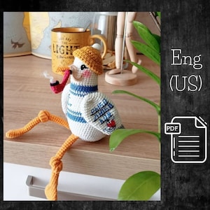May include: Crochet amigurumi pattern for a sailor seagull with a yellow hat, blue and white striped shirt, and a red pipe. The pattern is available in English (US) and includes a PDF download.