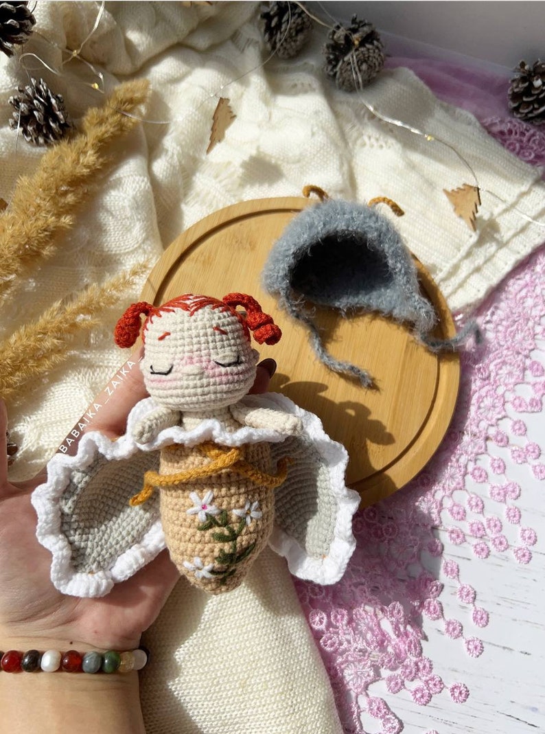 Detailed view of the amigurumi butterfly baby doll's face, showcasing its delicate handmade features. This eco-friendly crochet pattern allows for creating a soft, safe toy for children, filled with love and crafted with care.