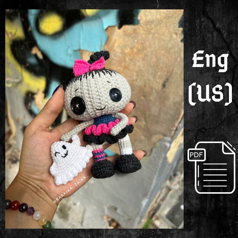 A handmade crochet Halloween doll with a small ghost in its hands, featuring a spooky yet cute design. The doll has a black and gray outfit with pink details, black boots, and a skull-like head. A perfect Halloween amigurumi decoration or gift for crochet lovers.
