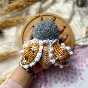 Amigurumi butterfly baby doll with open wings, displaying intricate crochet work. Perfect for adding a touch of whimsy to a handmade collection. An excellent DIY project for crafting with love, ideal for eco-conscious gifts.