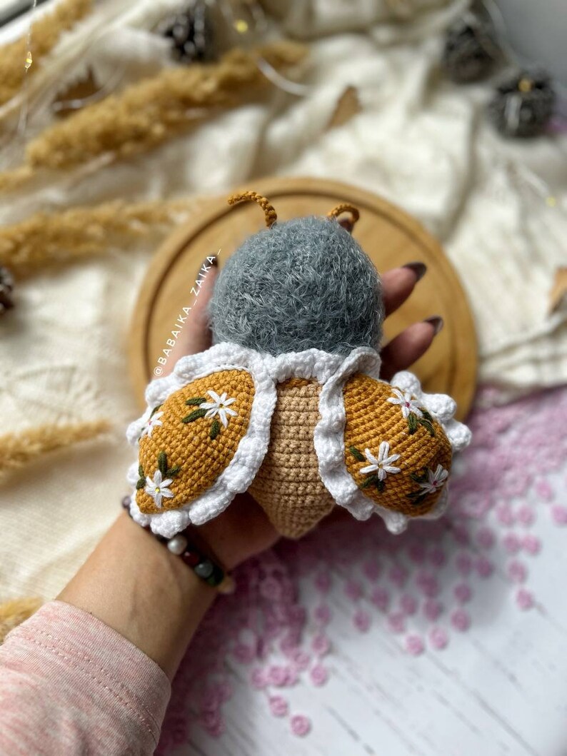 Amigurumi butterfly baby doll with open wings, displaying intricate crochet work. Perfect for adding a touch of whimsy to a handmade collection. An excellent DIY project for crafting with love, ideal for eco-conscious gifts.