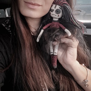 A gothic voodoo amigurumi doll in a unique handcrafted design, featuring black and red elements for a haunted Halloween look.