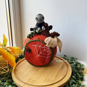 Amigurumi spider resting on a detailed crochet pumpkin house. Unique Halloween decor idea made with love. Ideal for handmade gift projects.