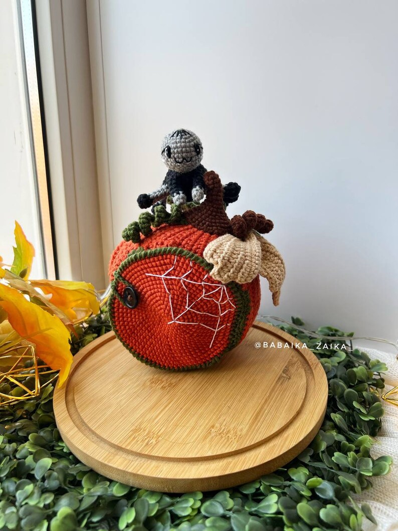 Amigurumi spider resting on a detailed crochet pumpkin house. Unique Halloween decor idea made with love. Ideal for handmade gift projects.