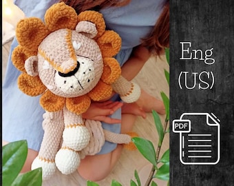 May include: A crocheted lion toy with a beige body, orange mane, and white face. The toy is being held by a person wearing a blue shirt. The image includes the text "Eng (US)" and "PDF".