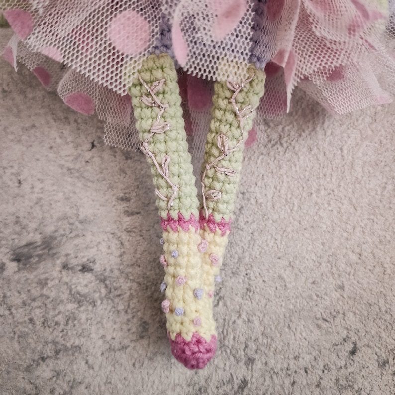 Close-up of the doll's face, highlighting intricate amigurumi details and button accents.
