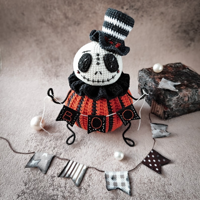 Close-up of the Jack pumpkin doll’s face, focusing on the creepy yet charming expression with stitched details. The striped hat and black frilly collar complete the Halloween look.