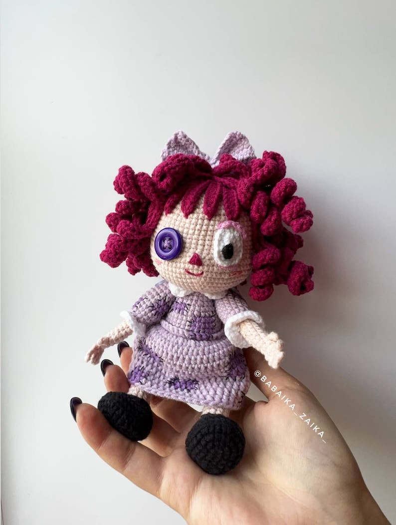 Close-up of the crochet doll with visible hand details, showing the intricate texture of the lavender dress and hair curls.