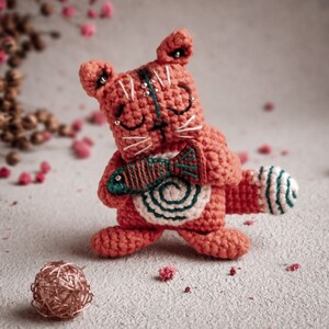 Handmade crochet cat with a tiny fish, designed with eco-friendly materials. This digital amigurumi pattern makes a great DIY craft project for a unique gift.