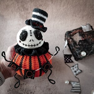 The back view of the Jack pumpkin doll, highlighting the carefully stitched spiderweb design on the back of the head and the tall black and white striped top hat.
