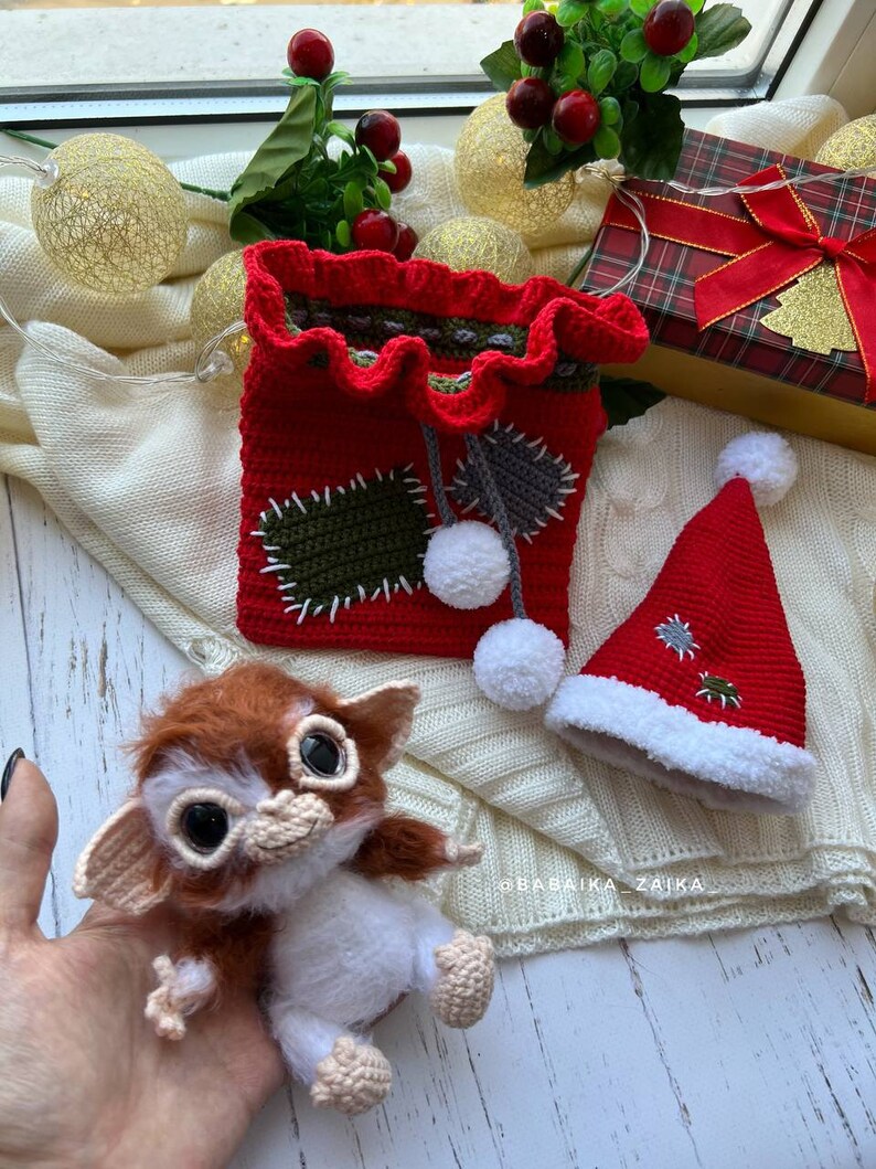 Unique handmade Gizmo amigurumi toy with Christmas bag, perfect for kids, collectors, and festive decor.
Gizmo toy wearing a Santa hat, sitting next to a handmade crochet Christmas bag, eco-friendly and collectible gift idea.