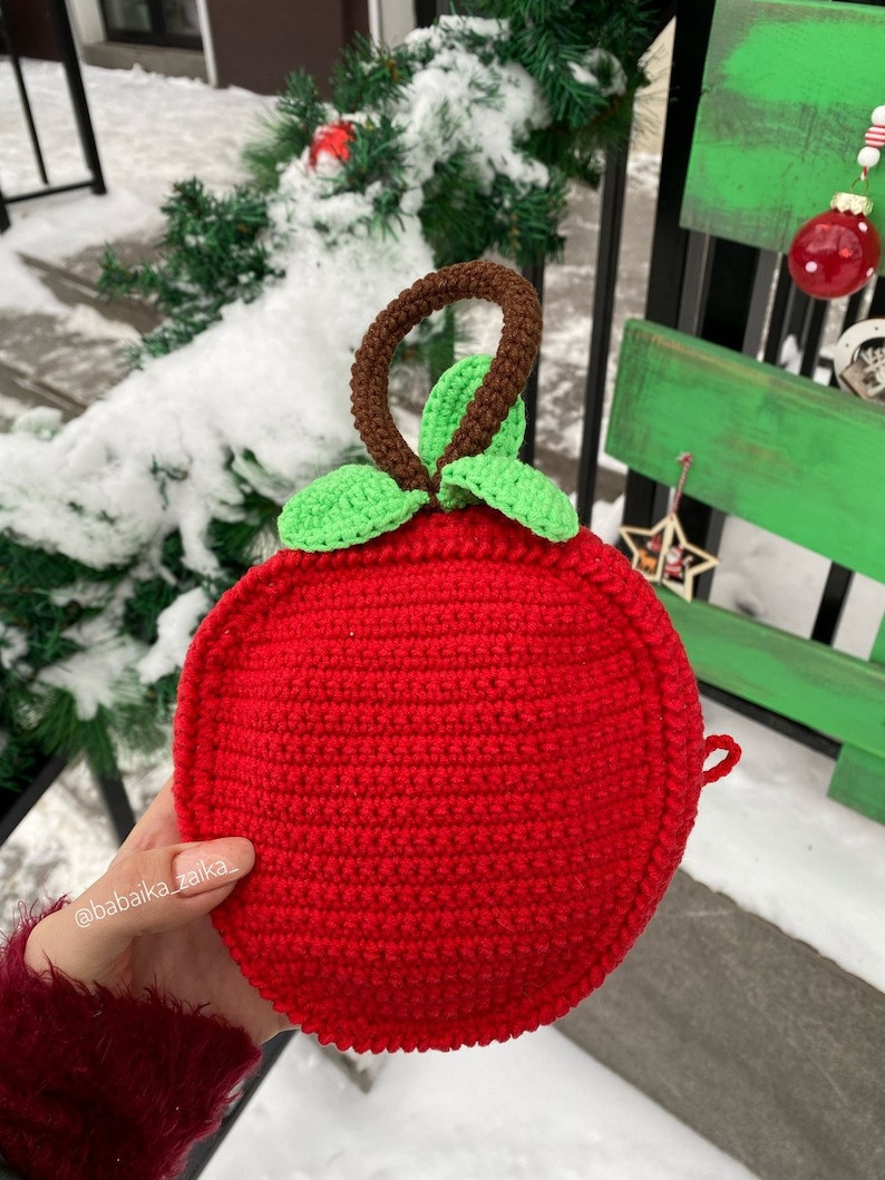 Two crochet foxes set against natural greenery, highlighting their handmade charm. A digital pattern for eco-conscious gifts.