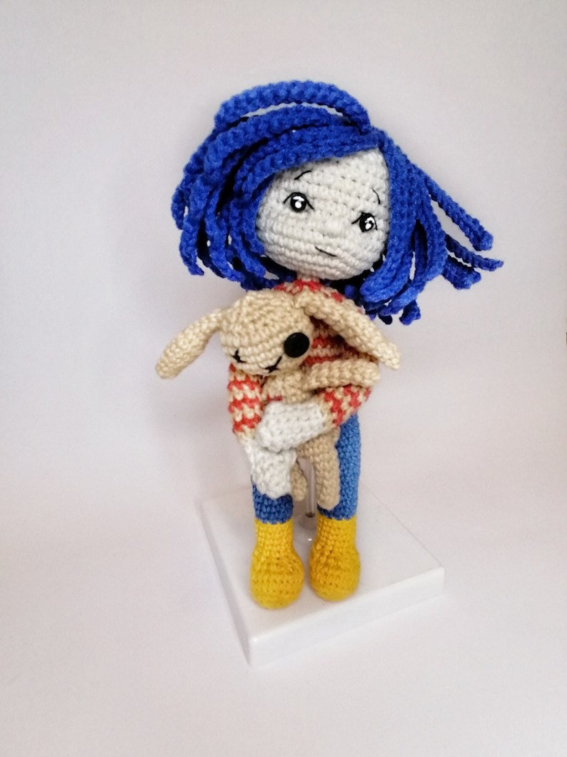 A detailed view of the Coraline doll and voodoo bunny together, showcasing the intricate crochet texture and handmade details.e crochet texture and handmade details.