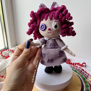 The doll placed on a decorative textile, showcasing its posture and detailed craftsmanship.
