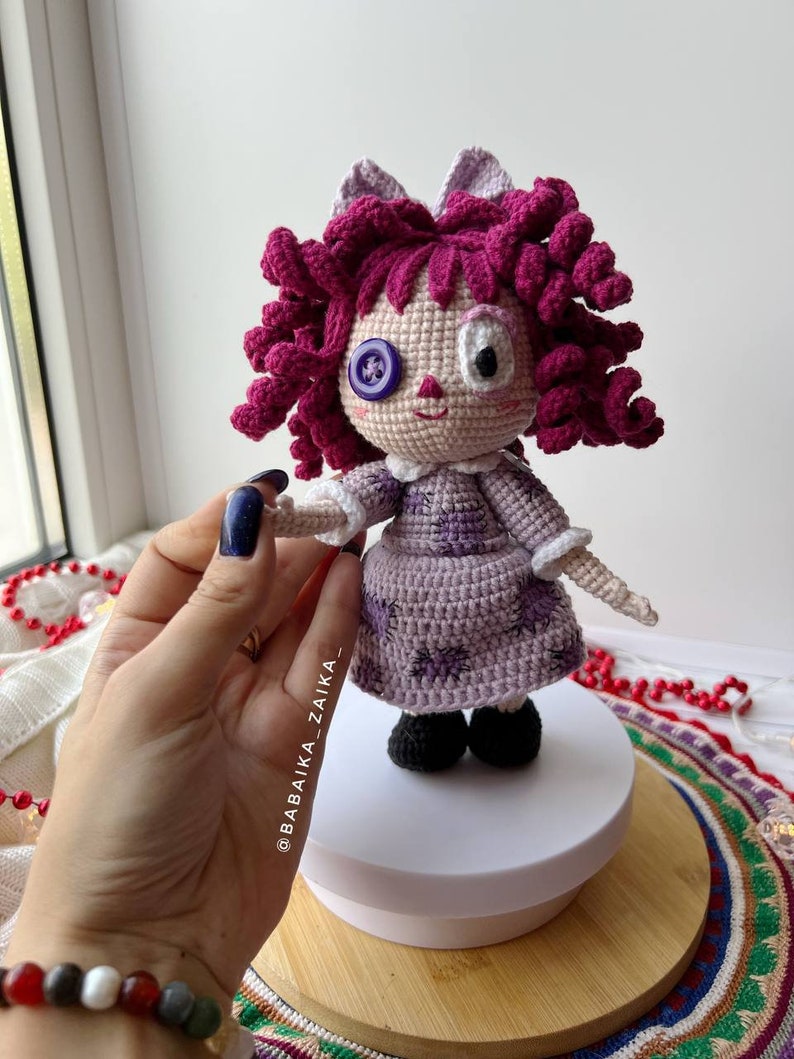 The doll placed on a decorative textile, showcasing its posture and detailed craftsmanship.