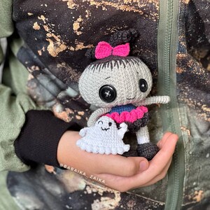 A close-up shot of the doll being held, highlighting its expressive face and fine crochet details. This amigurumi pattern is perfect for those who love Halloween crafts and unique handmade gifts.