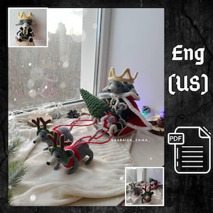 May include: A crocheted gray mouse wearing a gold crown and red cape sits in a sleigh pulled by two gray crocheted reindeer. The sleigh is decorated with a green crocheted Christmas tree. The image includes the text "BABAIKA_ZAIKA_" and "Eng (us)".