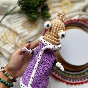 Amigurumi Kinger pattern with a purple robe and white trim, displayed in natural lighting to highlight craftsmanship.