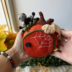Handmade crochet pumpkin house with an open lid revealing an adorable amigurumi spider. DIY Halloween decor or a unique handmade gift.
