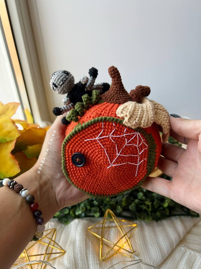 Handmade crochet pumpkin house with an open lid revealing an adorable amigurumi spider. DIY Halloween decor or a unique handmade gift.