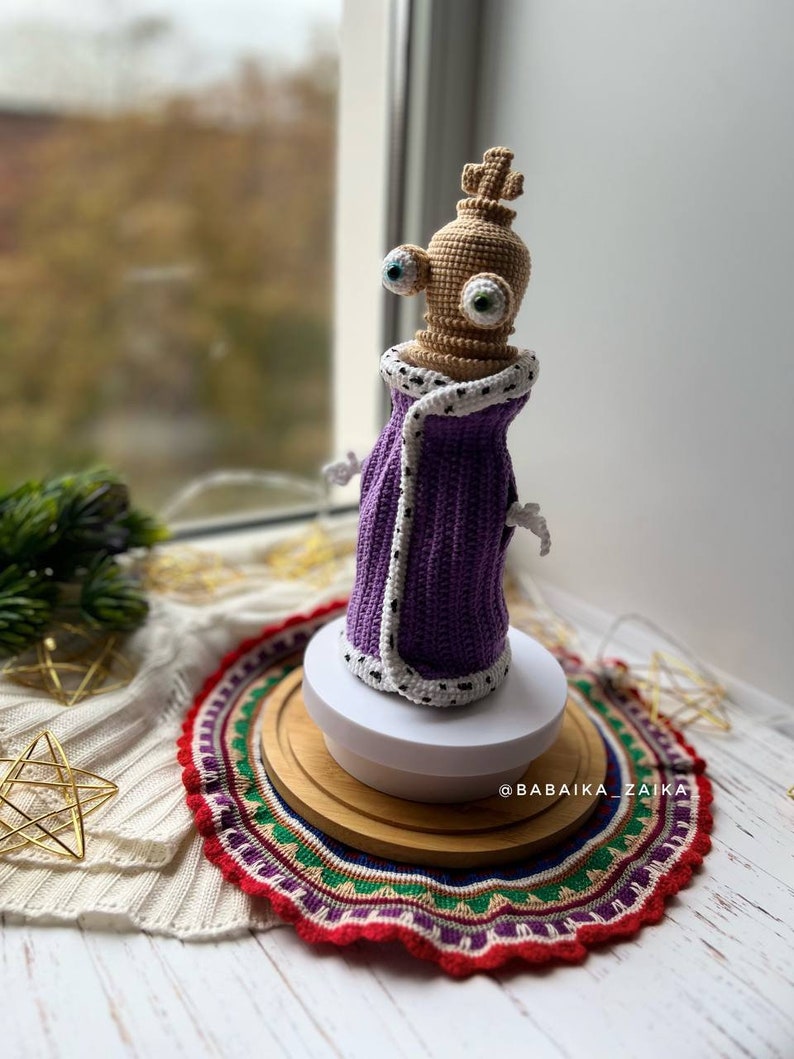 Detailed crochet work of a Kinger doll featuring expressive eyes and a whimsical design, great for Halloween decorations.