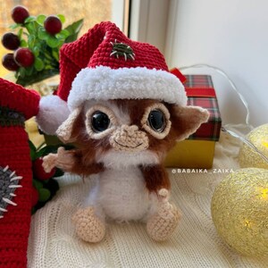 Crochet Gizmo toy holding a small Christmas bag, perfect DIY holiday decoration, unique and eco-friendly design.