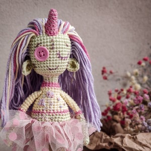 Detailed view of a handmade crochet doll with a purple and pink color scheme, designed for DIY crafting.